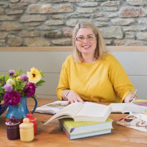 Kate writing at table with books around her